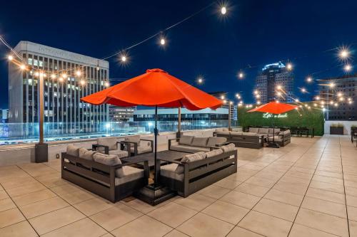 a patio with a table with an umbrella and couches at Hotel Mai Downtown Long Beach in Long Beach