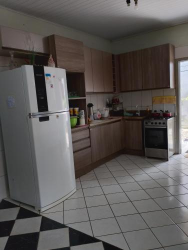 a kitchen with a white refrigerator and a tile floor at Pousada flores in Porto Velho