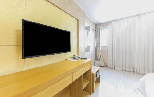 a living room with a flat screen tv on a wall at Joy Hotel in Jeju