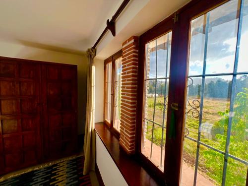 a room with two windows and a view of a field at Inka Tambo Hacienda in Cusco