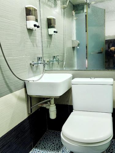 a bathroom with a white toilet and a sink at KK Hotel - Hostel - 24 hrs Reception in Flat C2 , Tsim Sha Tsui Building, 83-97 Nathan Road, Tsim Sha Tsui, Kowloon in Hong Kong