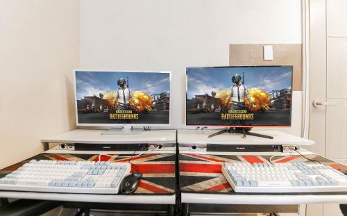 two computer monitors on a desk with two keyboards at Joy Hotel in Jeju