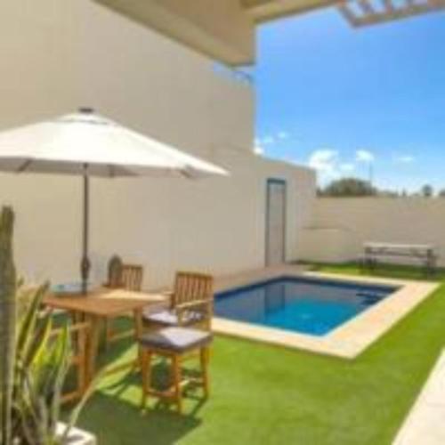 a backyard with a pool and a table and an umbrella at Casa Analía in San Carlos