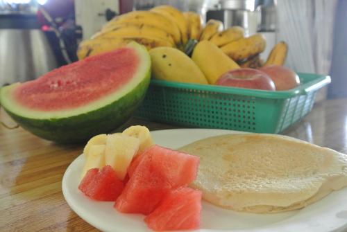 a plate of fruit with toast and watermelon and a basket of bananas at Tongatok Cliff Resort in Mambajao