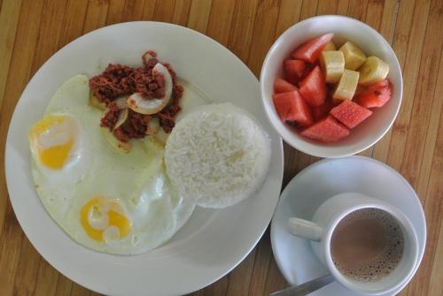 a plate of food with eggs and fruit and a cup of coffee at Tongatok Cliff Resort in Mambajao