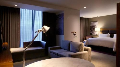 a hotel room with a bed and a chair and a lamp at Fiesta Americana Mexico Toreo in Mexico City