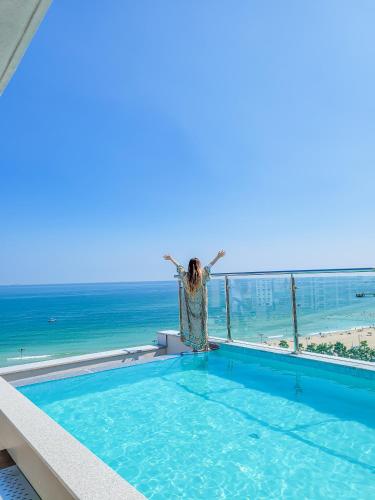 a woman standing on the edge of a swimming pool overlooking the ocean at Paul Mare Pool Villa in Busan