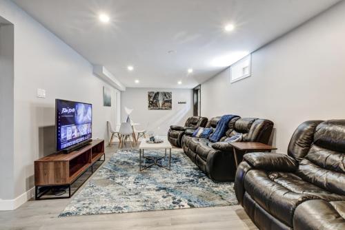 a living room with leather furniture and a flat screen tv at Luxury & private 3 bed basement unit kitchen, wifi, park, mall in London