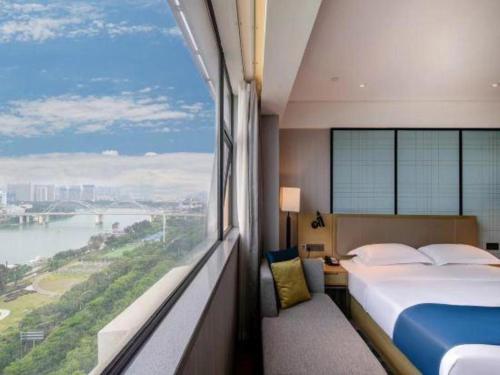 a hotel room with a bed and a large window at Echarm Hotel Nanning Chaoyang Square River View in Nanning