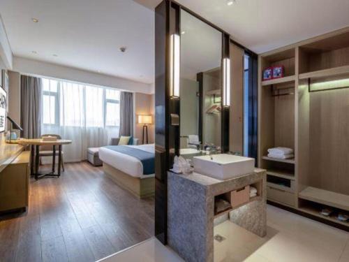 a hotel room with a bathroom with a bed and a sink at Echarm Hotel Nanning Chaoyang Square River View in Nanning