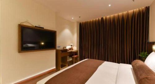 a hotel room with a bed and a flat screen tv at James Joyce Coffetel Shijiazhuang the Mixc Jinyuan Tower Airport Bus in Shijiazhuang