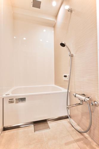 a shower in a bathroom with a white wall at Cocoro404 in Kichijōji
