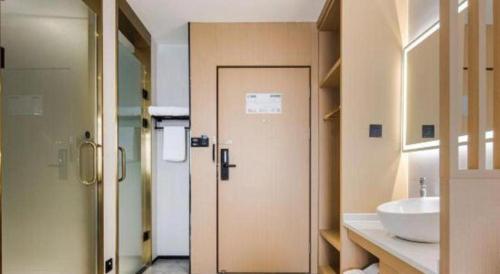 a bathroom with a sink and a toilet and a door at GEM Hotel Changzhou Xuejia'aoyuan North High-Speed Railway Station in Changzhou