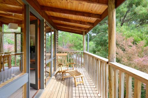 a wooden porch with a rocking chair on it at Stewarts Bay Lodge in Port Arthur