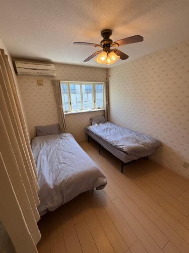 a bedroom with two beds and a ceiling fan at 京都観光に最適 ペットok 名神東インターから1分 3LDK無料駐車場付 京都駅から1駅 山科駅周辺 蹴上インクラインまで10分 in Kyoto