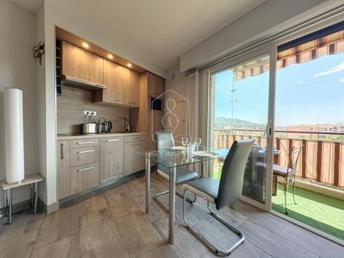 une cuisine avec une table en verre et une grande fenêtre dans l'établissement Le Beauséjour, studio with pool, parking, air conditioning, au Cannet