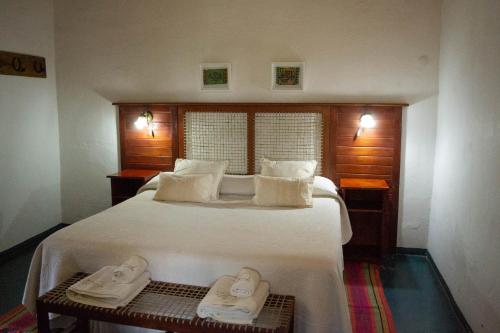 ein Schlafzimmer mit einem großen Bett mit zwei Paar Schuhen in der Unterkunft Estancia Santa María de las Casas Viejas in Mina Clavero