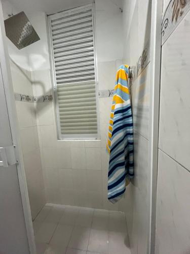 a bathroom with a shower with a window and a towel at Tayra Living Suites in Mocoa