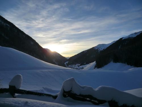 a snow covered mountain with the sun setting in the distance at Almhaus Pfister OHG in Predoi