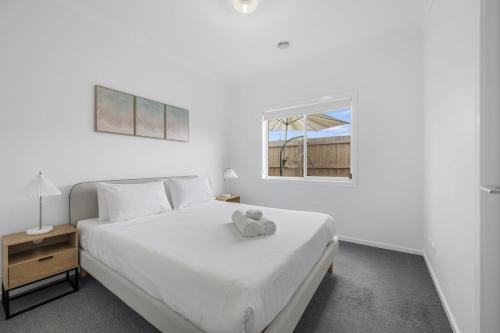 a white bedroom with a white bed and a window at Opal Villa in Warrnambool