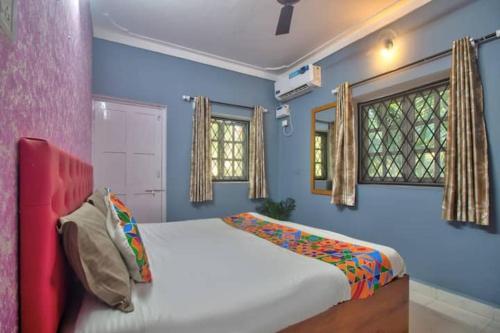 a bedroom with a bed and two windows at 5bhk Villa Near Caldolium Beach Goa in Candolim