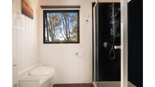 a small bathroom with a toilet and a window at Summer Lea 2 by Tiny Away in Howes Creek