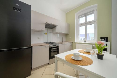 a kitchen with a table and a black refrigerator at Spacious Apartment with WiFi & Smart TV Remote Working by Noclegi Renters in Wrocław