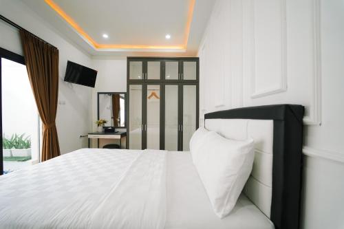 a bedroom with a white bed with a black headboard at Marina Villa 1 in Yogyakarta