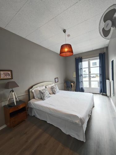 une chambre avec un grand lit blanc et une lampe dans l'établissement La Route Des Vins, à Belleville-en-Beaujolais