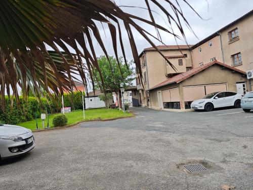 un parking avec deux voitures garées devant un bâtiment dans l'établissement La Route Des Vins, à Belleville-en-Beaujolais