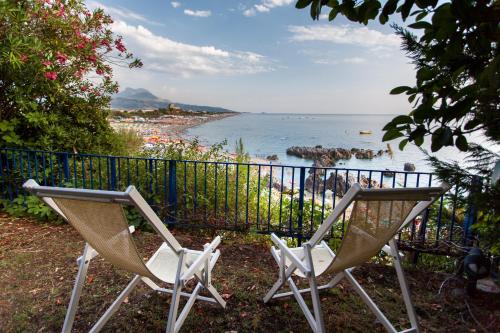two chairs sitting in front of a fence next to the water at Grand Hotel De Rose in Scalea