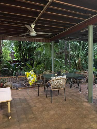 a patio with tables and chairs and a ceiling fan at Cosy room tropical garden in Jingili