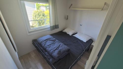 un petit lit dans une chambre avec une fenêtre dans l'établissement Magnifique Mobilhome au camping le Chateau de Galaure, à Châteauneuf-de-Galaure