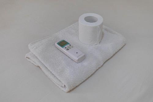 Funny Homestay 2 في غيلي تراوانغان: جهاز تحكم عن بعد موضوع على منشفة بجوار لفة من ورق التواليت