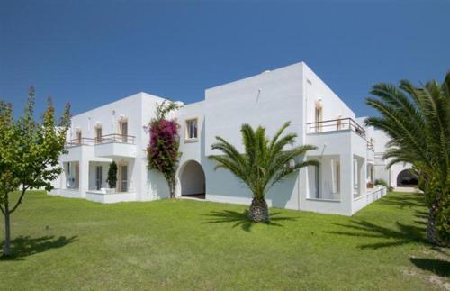 a large white house with palm trees in the yard at Alexandra Beach in Kos Town