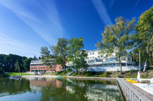 a building next to a body of water at Hotel Port Doksy in Staré Splavy