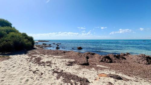 a beach with rocks and the ocean on a sunny day at Family Getaway Cabin 50 in Broadwater