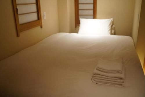 a white bed with a white pillow and towels on it at Softlight Inn Asakusa Tokyo in Tokyo