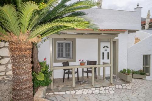 a table in front of a house with a palm tree at MAKIS VILLAGE-APARTMENTS in Ayia Evfimia