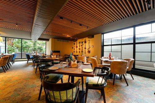a restaurant with wooden tables and chairs and windows at TGI Oberon in Bengaluru