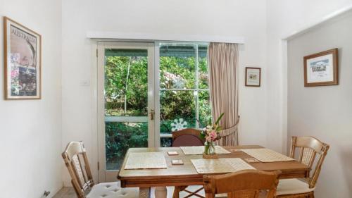 Un comedor con una mesa y una ventana. en Crabapple Southside Mountain Cottage Pet Friendly, en Wentworth Falls