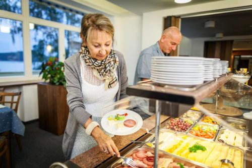 a woman is preparing food at a buffet at Hotel Port Doksy in Staré Splavy