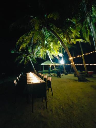 a table and chairs on the beach at night at Maa Thundi in Fuvahmulah