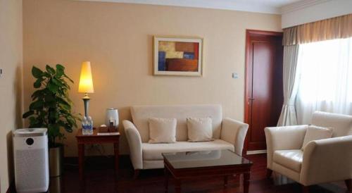 a living room with a white couch and a table at Jianguo Garden Hotel in Beijing
