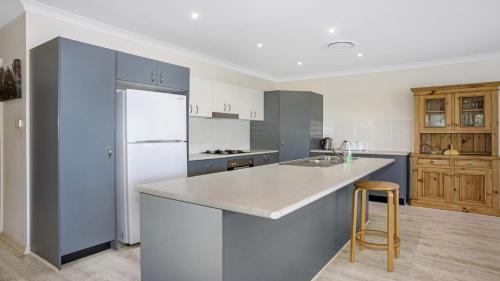 a kitchen with blue cabinets and a white refrigerator at Refresham Katoomba South in Katoomba