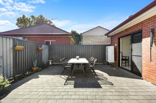 a patio with a table and chairs and a fence at Clay and Clover in Thebarton