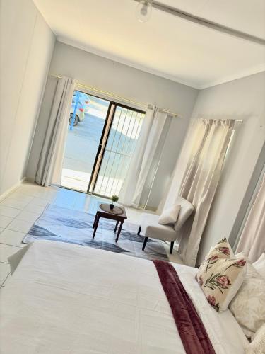 Un dormitorio con una cama y una silla y una ventana. en The Nest- on Knowling Street, en Grahamstown
