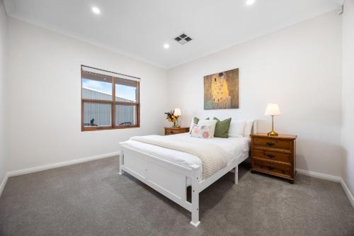 a white bedroom with a bed and a window at Clay and Clover in Thebarton