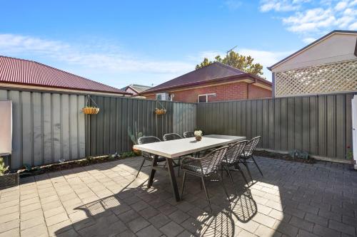 a table and chairs on a patio with a fence at Clay and Clover in Thebarton