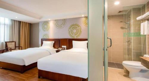 a hotel room with two beds and a shower at GreenTree Inn Nanning Langdong Hotel in Nanning